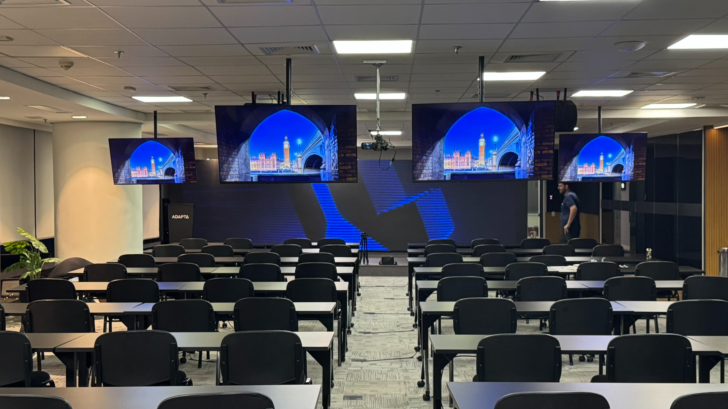 Auditório corporativo com telas suspensas em formato arena
